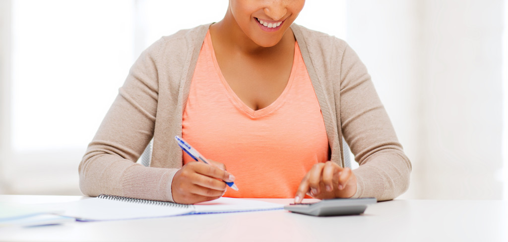 business and tax concept - african businesswoman working with calculator in office