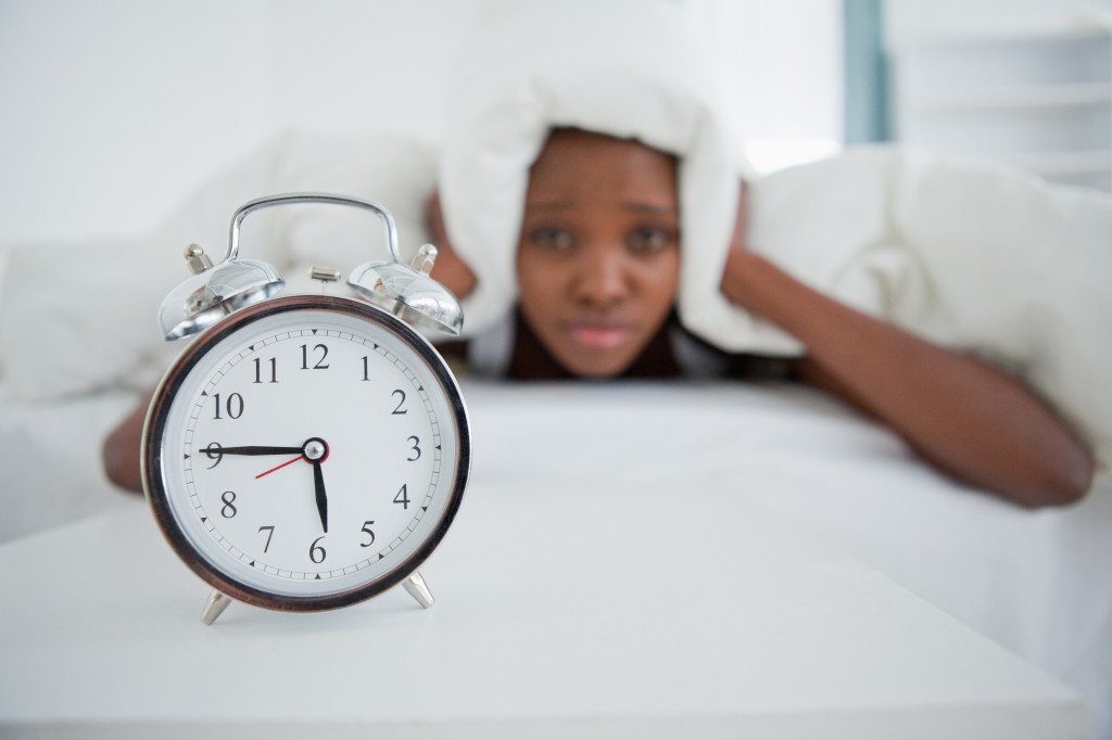 Woman being awakened by her alarm clock in her bedroom